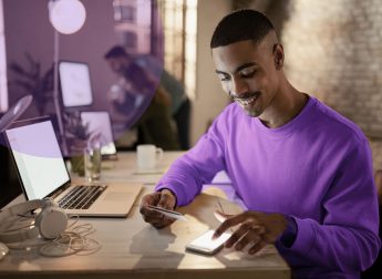 happy-african-american-entrepreneur-using-mobile-phone-credit-card-from-online-payments-while-working-night-office (1)